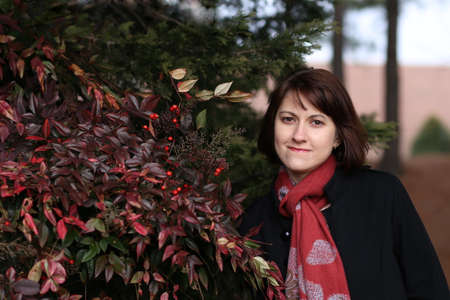 Girl in black coat near bush with red berries の写真素材