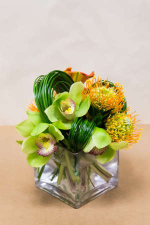Floral arangement with Mango Calla Lilies, Cymbidium orchids, Protea yellow pin cushion and greenery in square vaseの写真素材