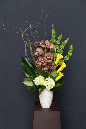 Floral arangement with Calla lilies, Cymbidium and James Storey orchids, Hydrangea, Curly willow, moluccella and greenery in white cylinder vaseの写真素材