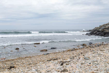 Rocky ocean shore windy overcast, yellow and brown stones and pebbles. Waves