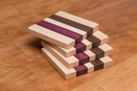 Set of four hardwood coasters with different layers of maple, walnut and purple heart woodの写真素材