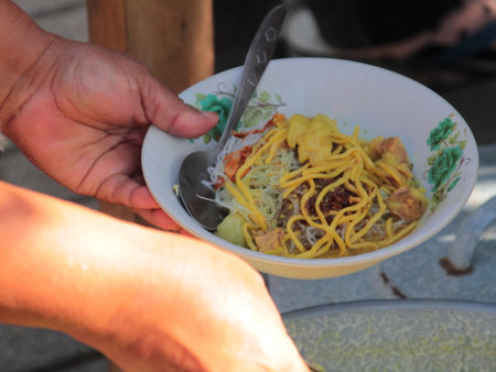 a bowl of soto, a typical Indonesian food with shredded chicken and vegetable toppingsの写真素材