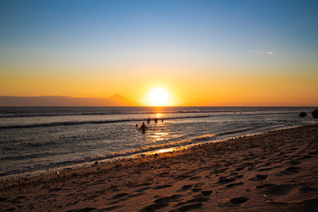 people playing and watching the sunset on the beachの写真素材