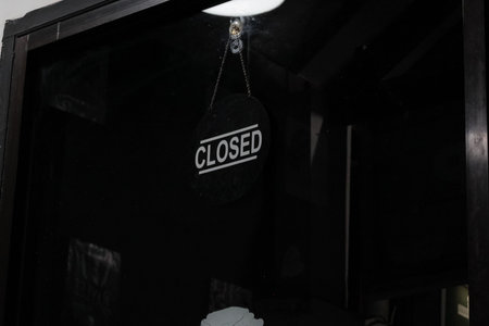 Closed Sign Hanging on Dark Glass Doorの写真素材