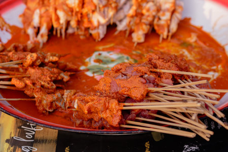 Raw chicken skewers covered in a vibrant red marinade ready for grilling