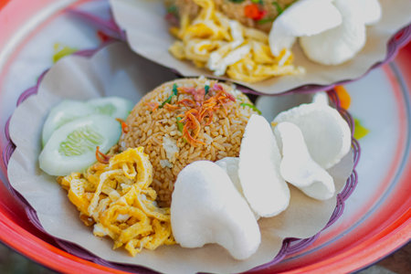 Traditional Indonesian fried rice with kerupuk and cucumber slices being servedの写真素材