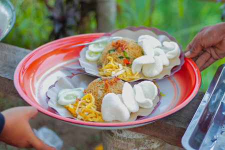 Traditional Indonesian fried rice with kerupuk and cucumber slices being servedの写真素材