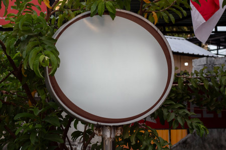 Blank oval sign template outdoors surrounded by green leaves.の写真素材