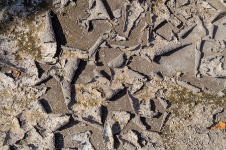Texture of dry cracked earth ground with peeling gray mud layer and rough surface detail.の写真素材