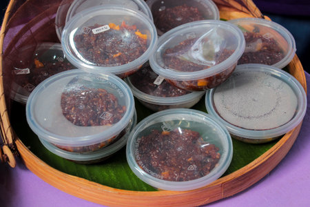 Close-up of packaged spicy relish in clear, round, microwave-safe plastic containers stacked inside a traditional bamboo trayの写真素材