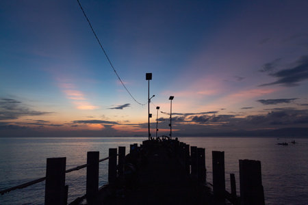 Dock Silhouette at Dusk with Colorful Sky Reflection on Calm Ocean Water for Tranquility and...