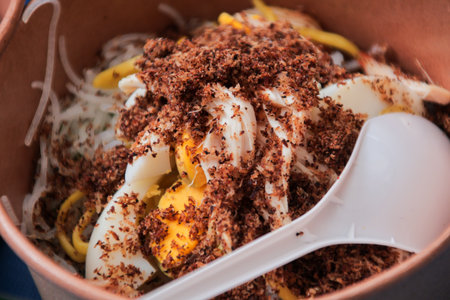 Savory noodle dish topped with egg and grated coconut in bowl, offering a glimpse into authentic...