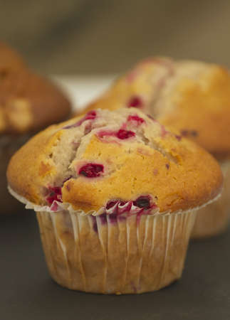 Three freshly baked muffins on a slate table