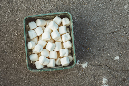 White marshmallows in a plastic box on the asphalt background.の素材