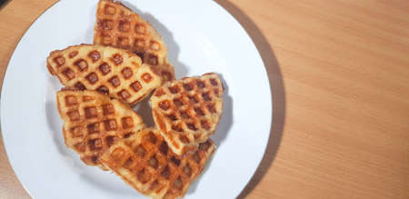 Stack of Croissant Waffle or Croffle served in white plate and wooden background, Selective focus image.の写真素材