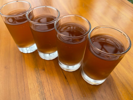 Fresh cold Apple juice in four clear glass with wooden background serves for breakfastの写真素材