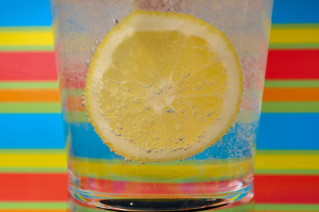Lemonade fizzy drink in a clear glass with colorful background showing fizzy bubbles good for your multimedia content creation backgroundの写真素材