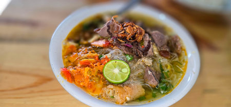 Indonesian style beef noodle soup called soto mie, freshly made soup with vermicelli rice noodle,...