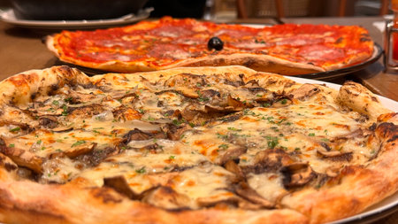 Freshly baked New York style pizza with melted mozzarella cheese and base tomato sauce close-up on a...
