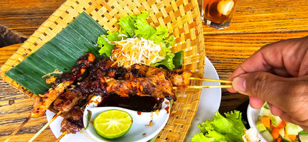 Chicken grilled satay skewers served with lime and peanut sauce on black, top view. Asian thai style food, good for cooking book idea, content creationの写真素材