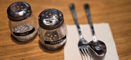 simple American diner style salt and pepper glass shakers sits on table with wooden background,...