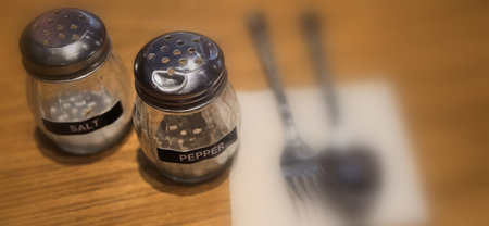 simple American diner style salt and pepper glass shakers sits on table with wooden background, selective focus background, good for recipe book or web blog creative content creationの写真素材