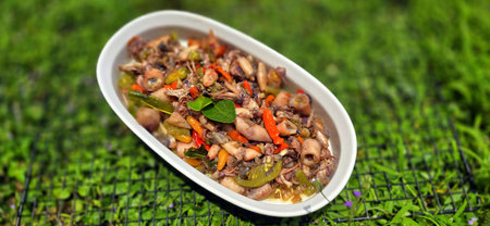 sauteed salty squid with black ink sauce with spicy seasoning called tumis cumi asin, is local Indonesian homemade cooking to include chili, ginger, and lime leaf served in a bowl, good for recipe bookの写真素材