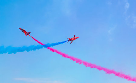 The red arrows performing maneuvers over blue sky in England, jet performing air acrobatic and...