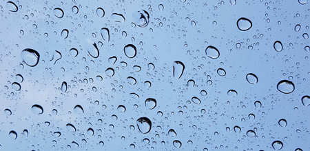 Rain and water droplets perspective through window glass surface against blue sky good for...
