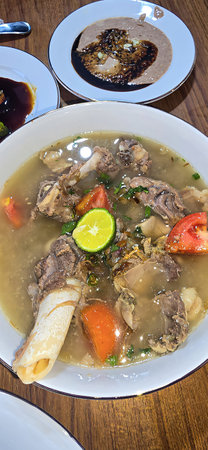 Bowl of hearty traditional lamb or mutton meat soup featuring chunks of meat and fresh vegetables,...