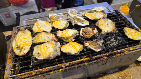 street vendor uses a torch flame to prepare delicious grilled oyster with flair and skill, showcasing the vibrant atmosphere of bustling night Thai markets. Good for recipe bookの写真素材
