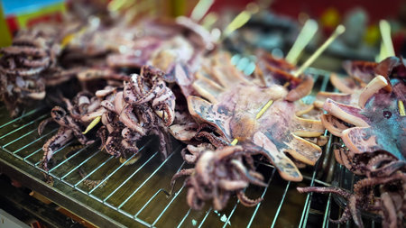 Freshly grilled barbecue squid on skewers displayed at an Asian street food market showcasing vibrant culinary traditions. Good for cooking multimedia contentの写真素材