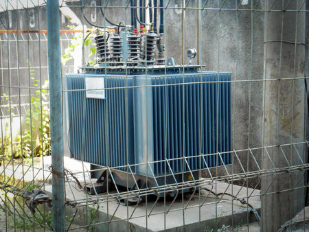 High Voltage Transformer Enclosed Behind Metal Fencing in an Industrial Setting, An image depicting...