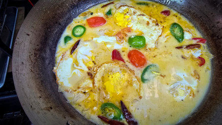 Rich Spicy Egg soup Dish with coconut milk and Vegetables in Rustic Pan, for illustrating authentic...