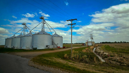 Grain silos on a farm with blue sky and white clouds