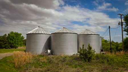 Grain silos on a farm with cloudy sky in the backgroundの写真素材