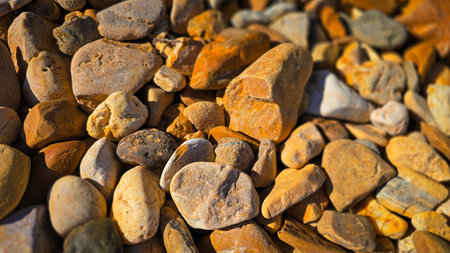 texture of a natural assortment of pebbles and river stones in warm earth tones, ideal for landscaping, garden borders, pathways, or decorative rock surfaces. Natural Pebbles And River Stones For Landscaping And Garden Decorの写真素材