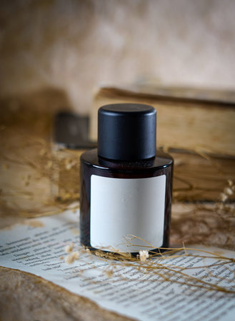 Dark Perfume Bottle With Blank Label Surrounded by aesthetic background, minimalist still life perfect for fragrance branding and beauty campaigns. sleek dark perfume bottle with a blank labelの写真素材