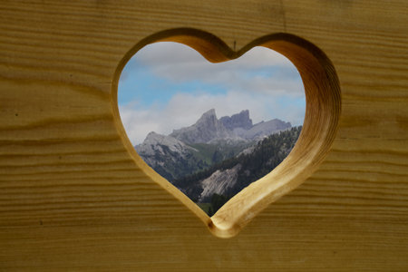 Heart shaped window in a wooden wall with a view of the Dolomitesの写真素材