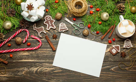 Christmas or New Year celebrates the background. Flat-lay, glittering toys, cookies, hot latte with marshmallow, cinnamon, candy, scissors on an antique wooden table, top view, copy spaceの写真素材
