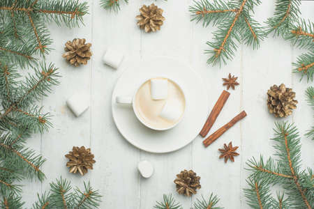 Christmas composition. A coffee with a marshmallow, pine cones, spruce branches on a wooden white...