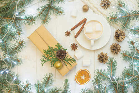 Christmas gifts, coffee with marshmallows, pine cones, spruce branches on a wooden white background....