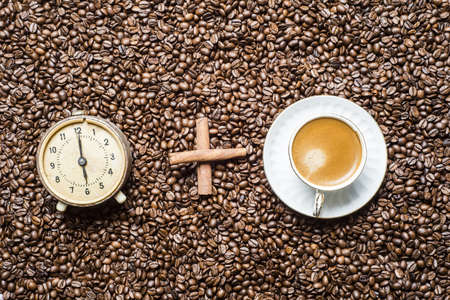 cup of coffee with an alarm clock on the background of coffee beans