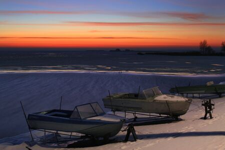 Sunset on the frozen river, boatの写真素材