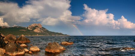 Rainbow over stormy seaの写真素材