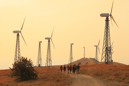 Group of people walking through fields with wind generatorsの写真素材