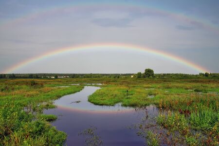 Rainbow over the river on sunsetの写真素材