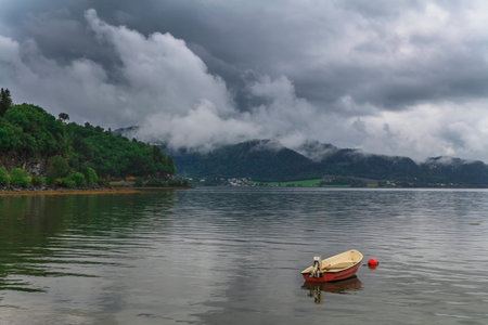 Fishing boat on a still lake and high mountains in background.の写真素材