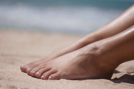women's feet and hands on the beach beautiful skinの写真素材