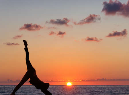 Girl practicing yoga against the background of the ocean and sunset.の写真素材